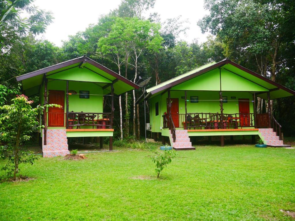 two green buildings with red doors in a yard at Mata Guesthouse in Ko Kood