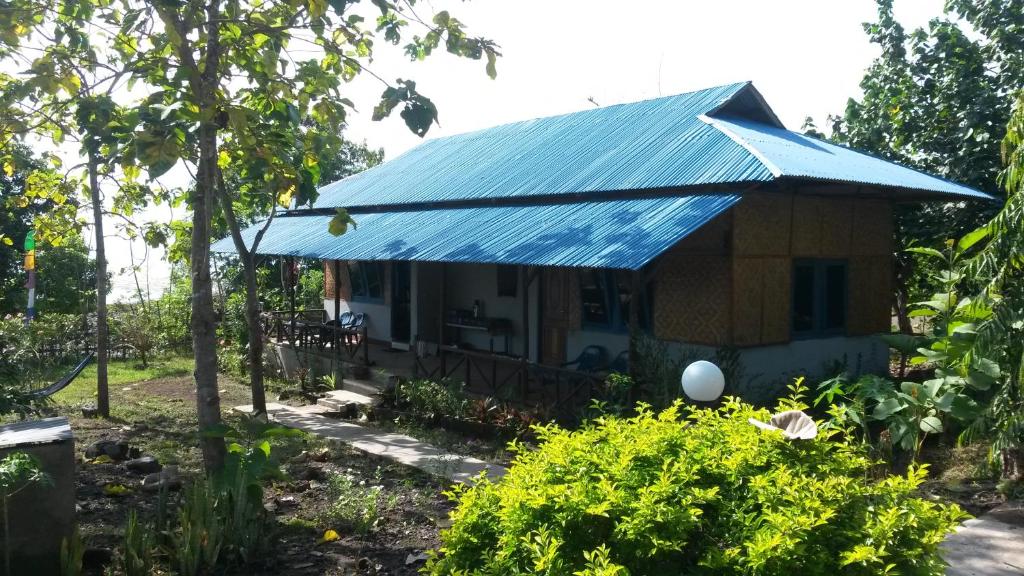 una pequeña casa con techo de estaño azul en Leko Lembo Guesthouse, en Keli