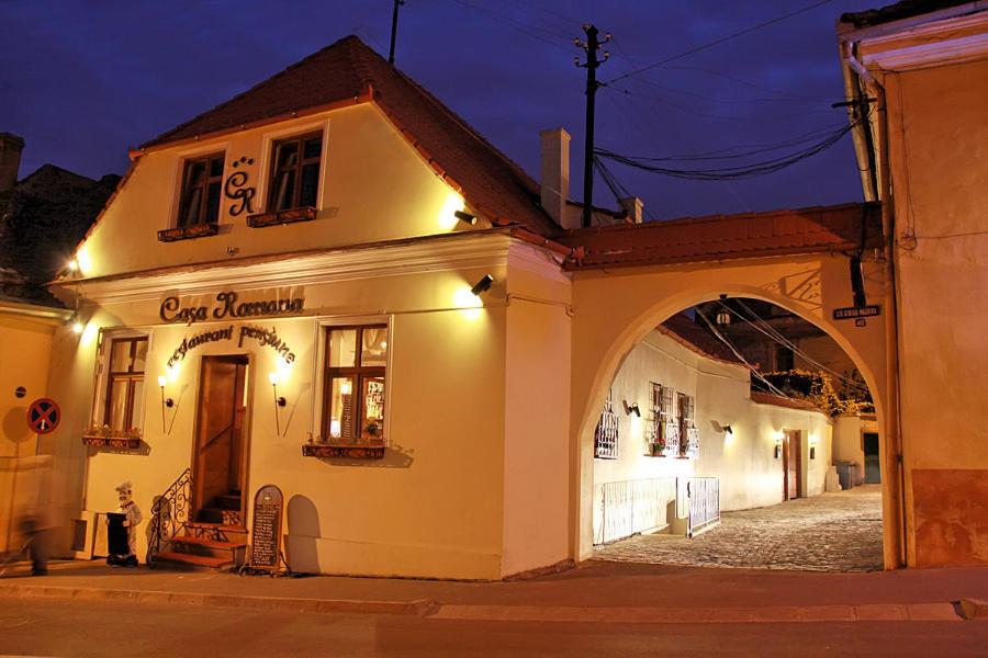 a building with an arch in a street at night at Casa Romana I in Sibiu