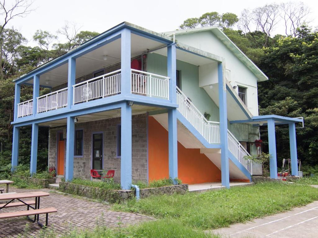 ein Gebäude mit blauen Säulen und einem Picknicktisch in der Unterkunft YHA Ngong Ping SG Davis Youth Hostel in Hongkong