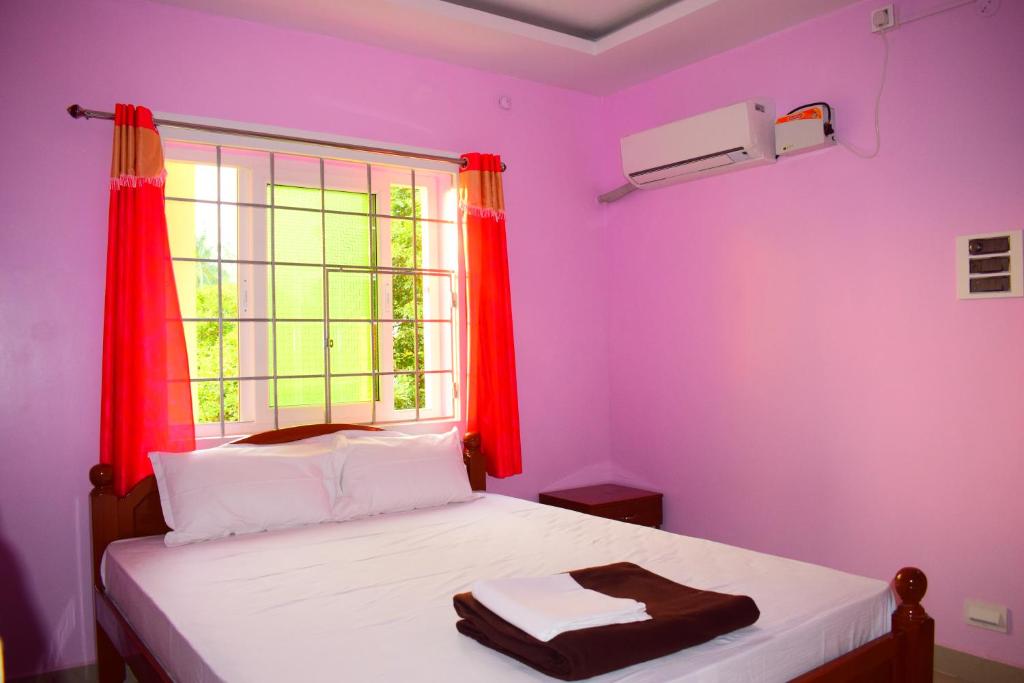 a bedroom with pink walls and a bed with a window at Harsha's Residency in kāraikāl