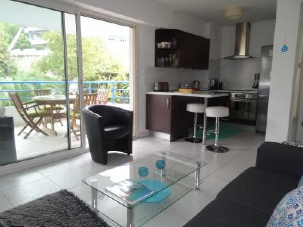 ein Wohnzimmer mit einem Sofa und einem Glastisch in der Unterkunft Modern one bedroomed apartment just off the Cannes Seafront with a terrace and pool access 1753 in Cannes