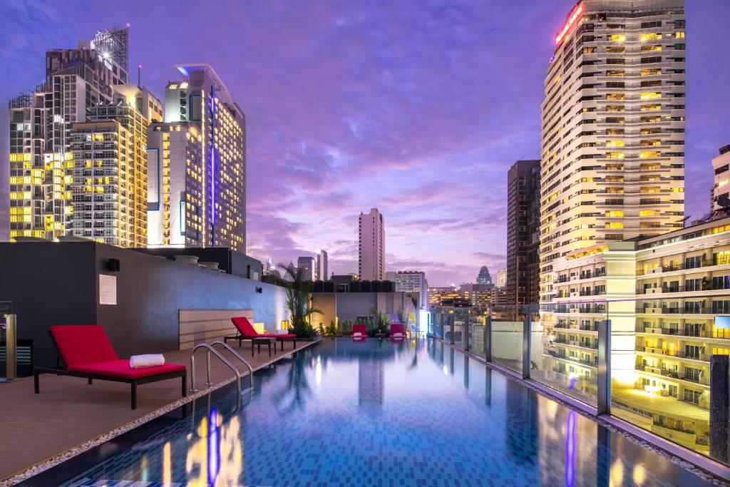 a rooftop pool with chairs and a city skyline at Travelodge Sukhumvit 11 in Bangkok