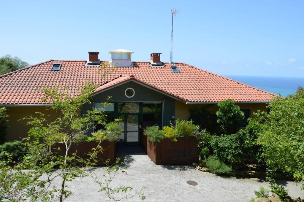 una casa con techo rojo con el océano en el fondo en Apartamentos Mar y Mar Agroturismo, en San Sebastián