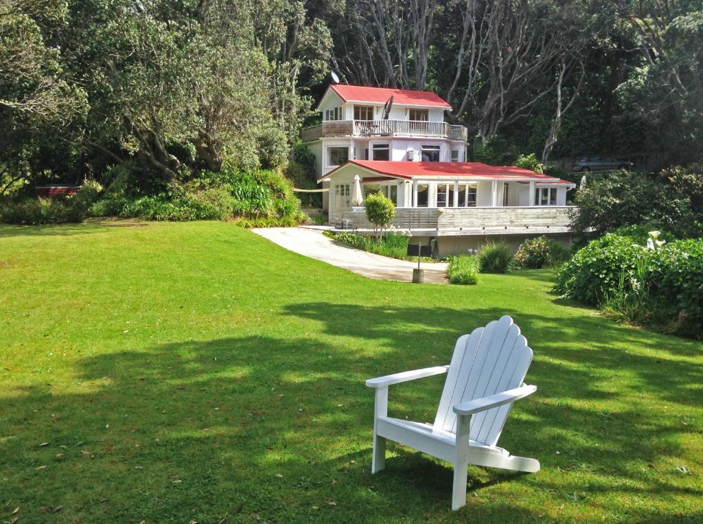 une chaise blanche assise dans l'herbe devant une maison dans l'établissement Ohiwa Seascape Studios, à Opotiki