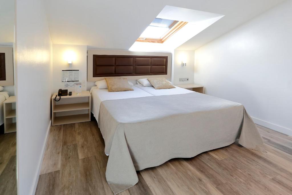 a bedroom with a large white bed and wooden floors at Hotel Santa Rosa, Blue Hoteles in Gijón
