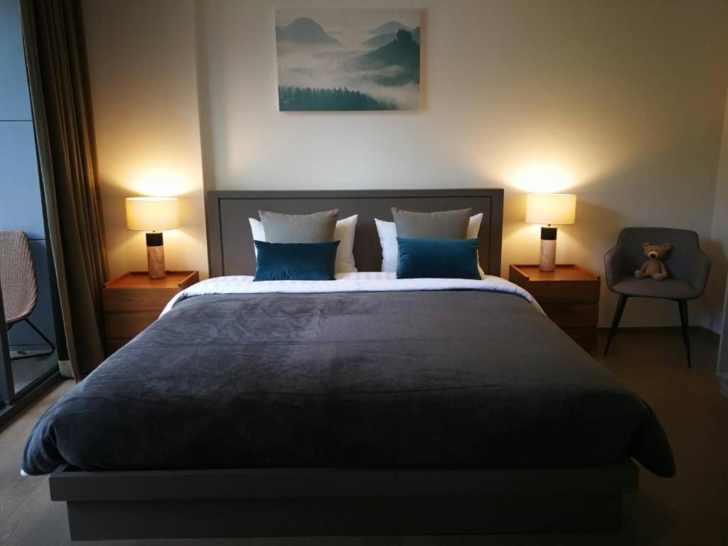 The Valley Khao Yai-2 Bed Room في Ban Huai Sok Noi: غرفة نوم بسرير كبير ومخدات زرقاء ومصباحين