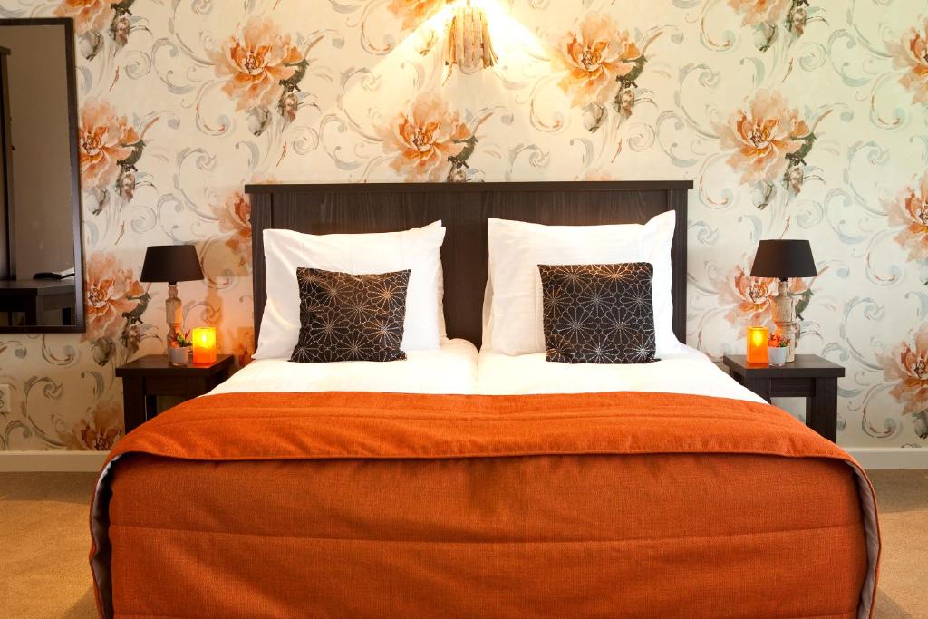 ein Schlafzimmer mit einem großen Bett mit orangefarbener Decke und Kissen in der Unterkunft Hotel-Herberg D'n Dries in Drunen