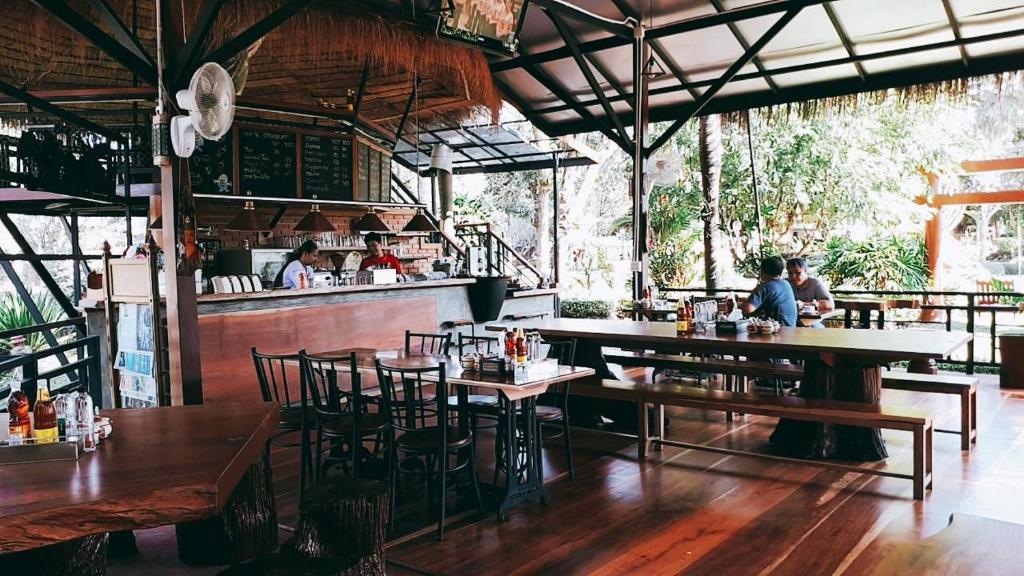 a restaurant with wooden tables and chairs and a bar at Chuanthanapanya Resort in Amphoe Sawang Daen Din