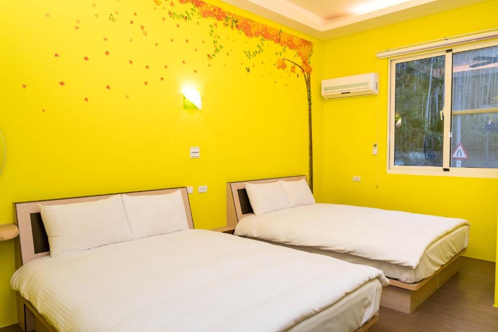 twee bedden in een kamer met een gele muur bij Clover B&B in Yuchi