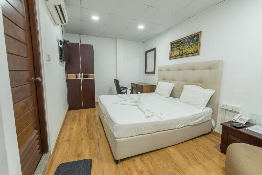 1 dormitorio con 1 cama blanca y teléfono en Metro City Hotel, en Colombo