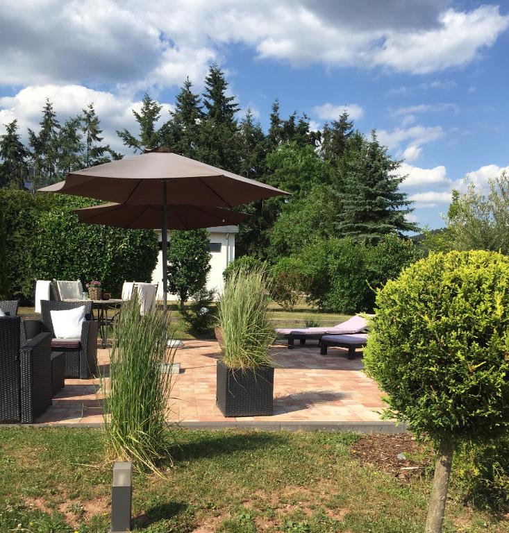 a patio with an umbrella and tables and chairs at Maxhof Trier in Trier