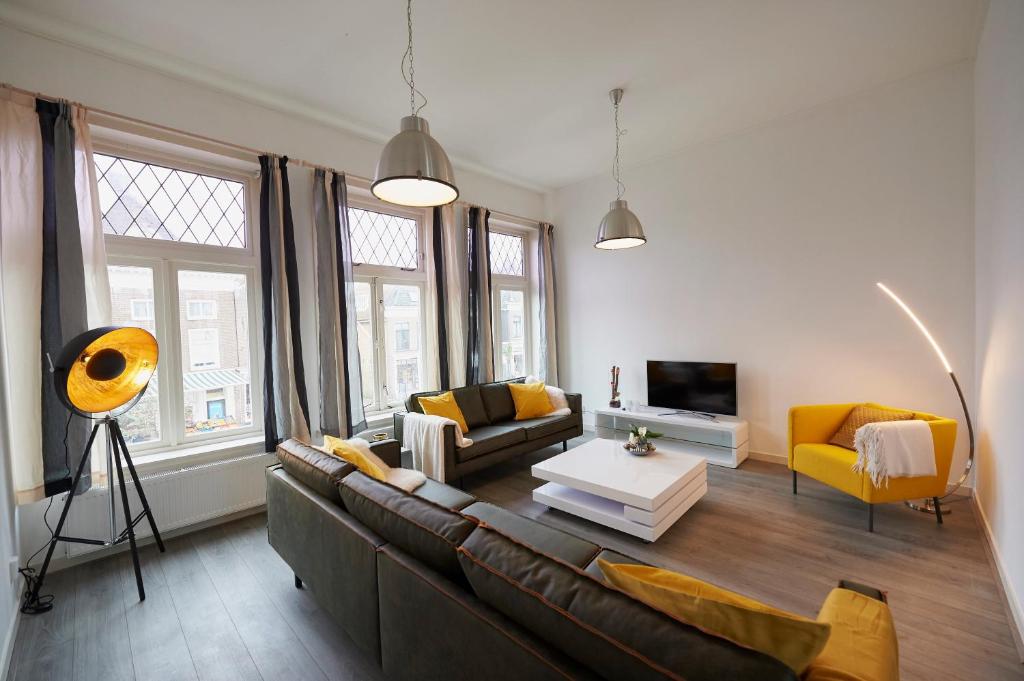 sala de estar con sofá marrón y sillas amarillas en Harlingen oldtown apartment, en Harlingen