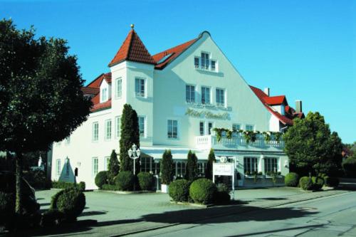 um grande edifício branco com um telhado vermelho em Hotel Daniels em Hallbergmoos