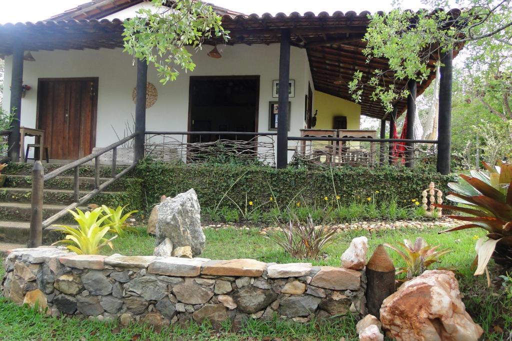 a house with a stone wall in front of a yard at Pousada Do Pequi in São Gonçalo do Rio das Pedras