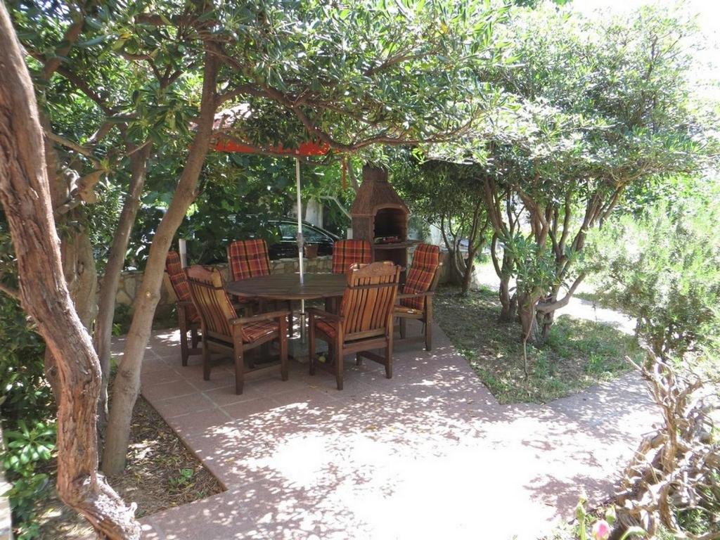 a patio with a table and chairs under an umbrella at Apartments & Rooms Nikica in Baška