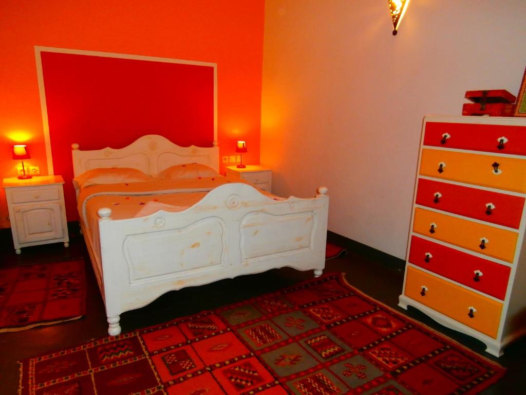 a bedroom with a white bed and a red wall at Maison Xanadu in Sidi Ifni
