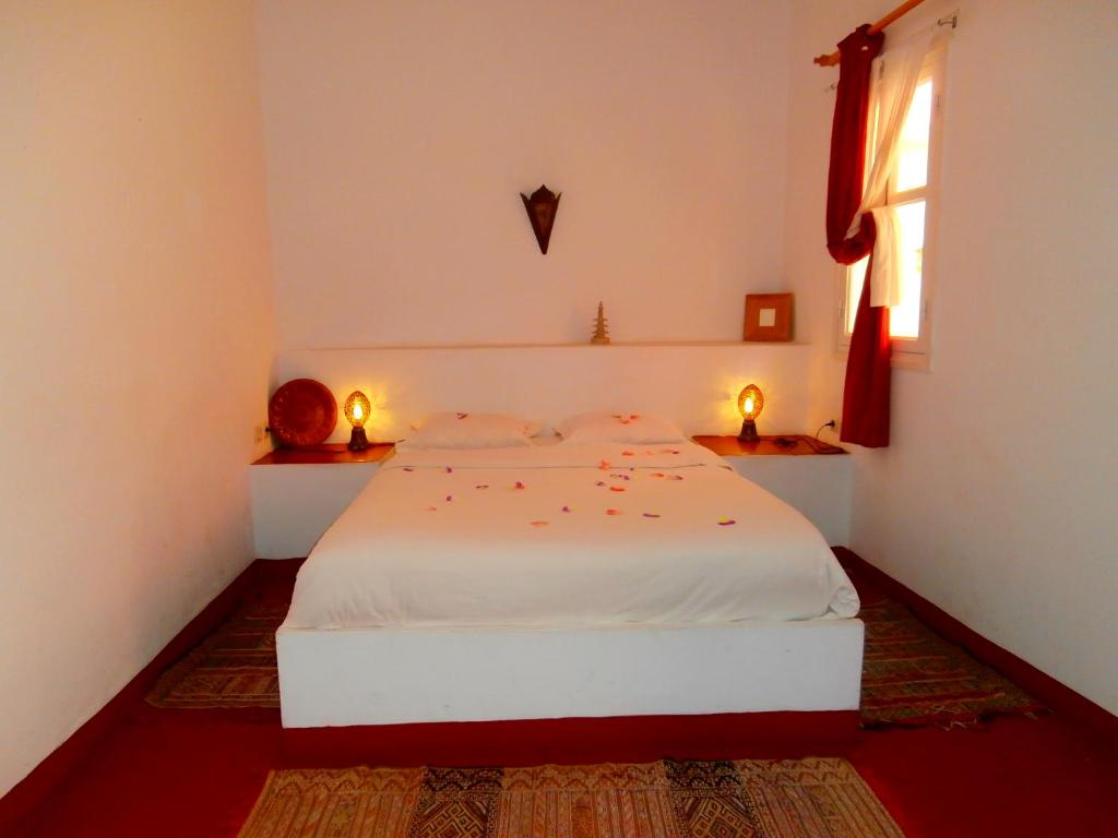 Cama blanca en habitación con ventana en Maison Xanadu, en Sidi Ifni