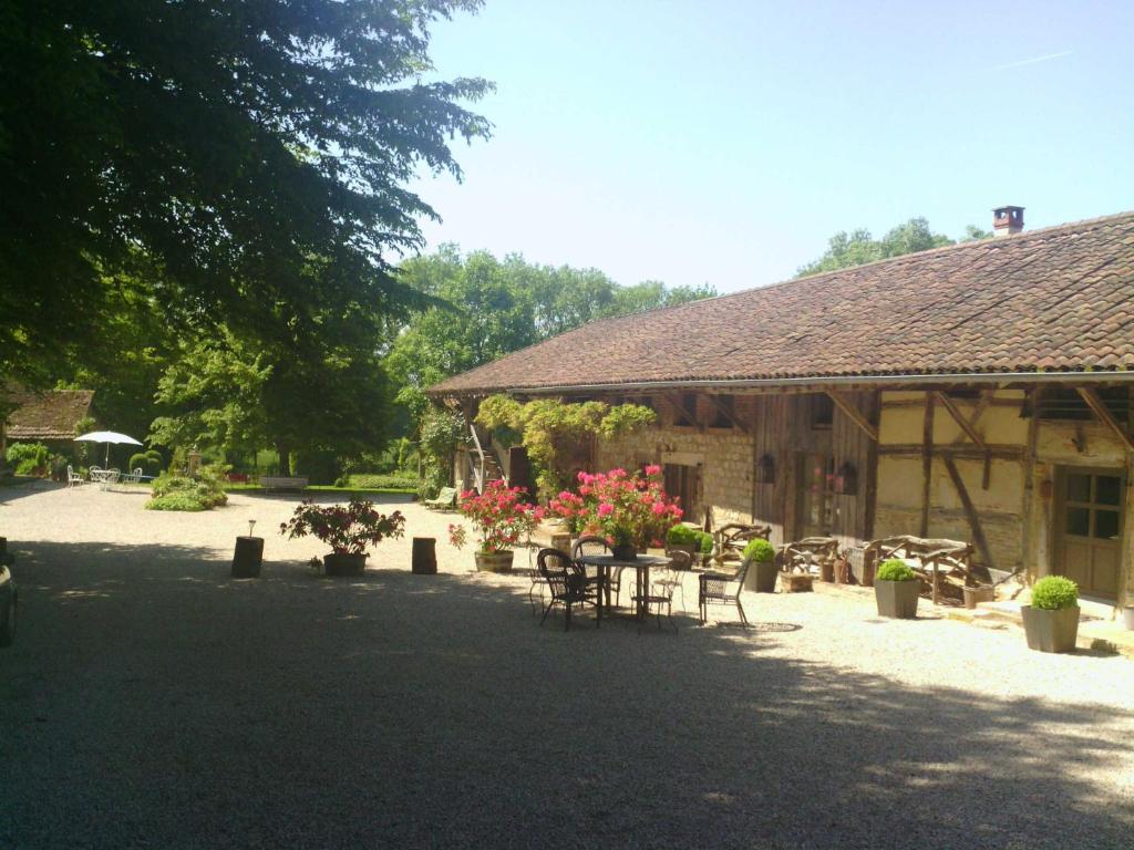 
a patio area with chairs, tables and umbrellas at La Ferme de Marie Eugénie in Bruailles

