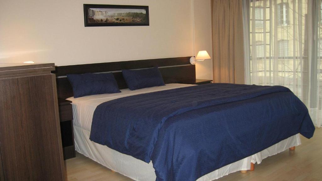 Córdoba Suites Recoleta في بوينس آيرس: غرفة نوم بسرير كبير مع بطانية زرقاء