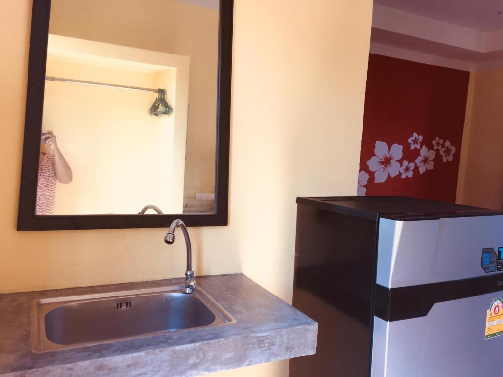 baño con lavabo, espejo y nevera en Chill land house, en Bang Tao Beach