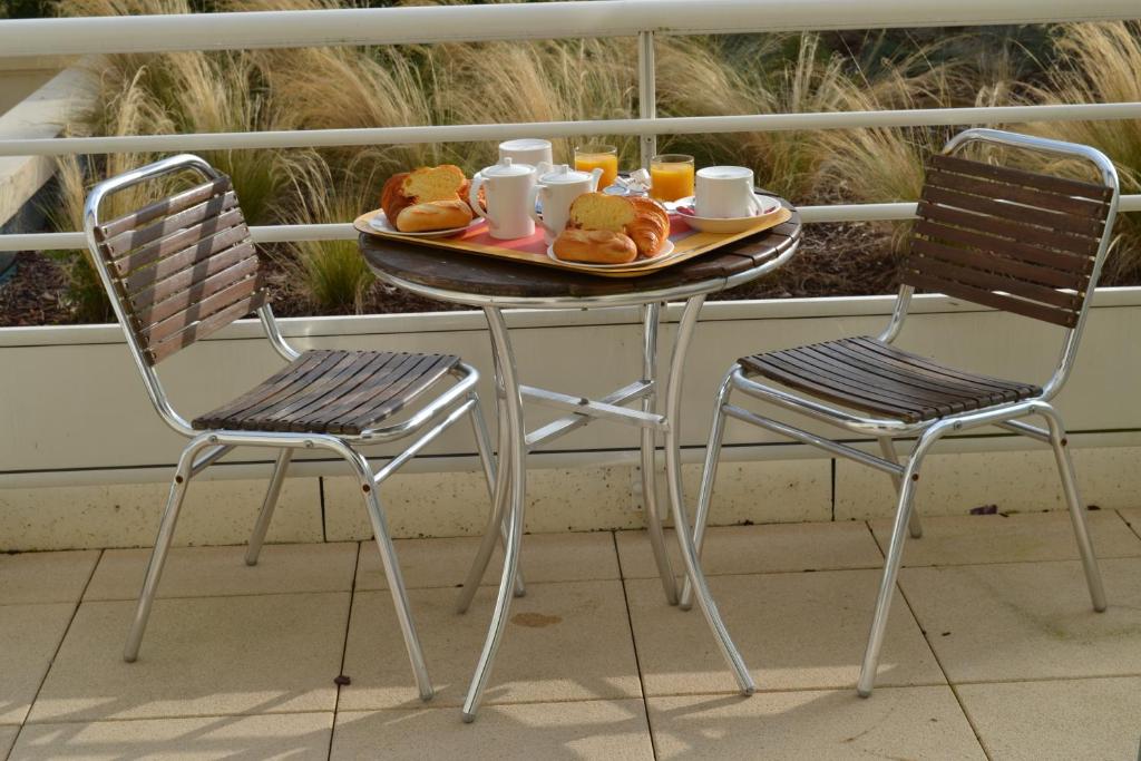 a table with two chairs and a tray of food at Almoria Hôtel & SPA in Deauville