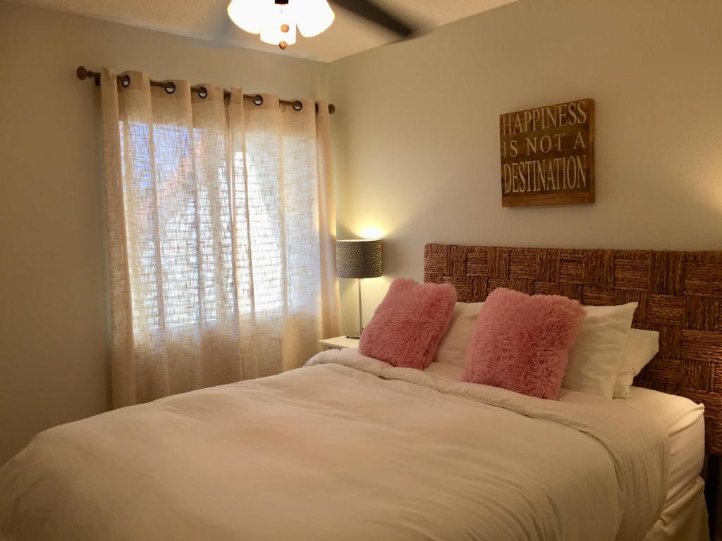 1 dormitorio con cama blanca y almohadas rosas en Wander Residence Condo near Fort DeSoto, en Tierra Verde