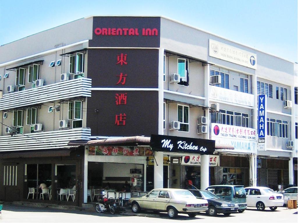 ein großes Gebäude mit davor geparkt in der Unterkunft Oriental Inn in Kuching