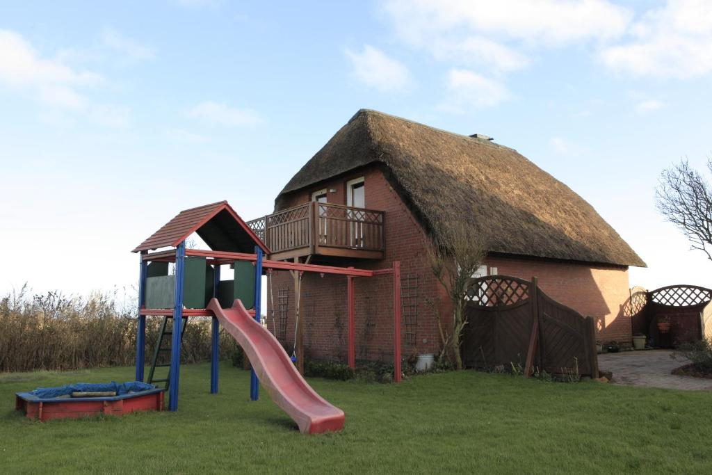 une maison avec une aire de jeux et un toboggan dans l'établissement Ferienwohung II (Schardeich), à Pellworm