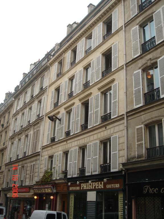 un grand bâtiment avec des fenêtres blanches à volets sur une rue dans l'établissement MULTIRESIDENCE L'ELYSEE Paris, à Paris