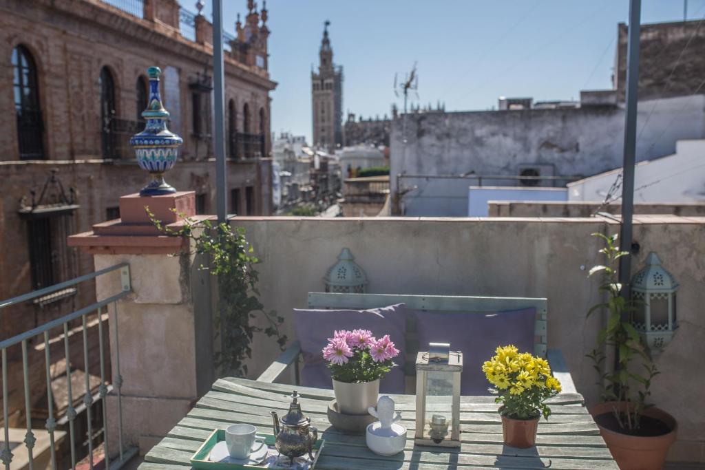 einen Tisch auf einem Balkon mit Blumen darauf in der Unterkunft Awesome Penthouse in Sevilla