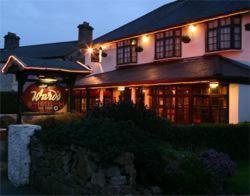 une grande maison avec un panneau de néon devant elle dans l'établissement Wards Hotel, à Galway