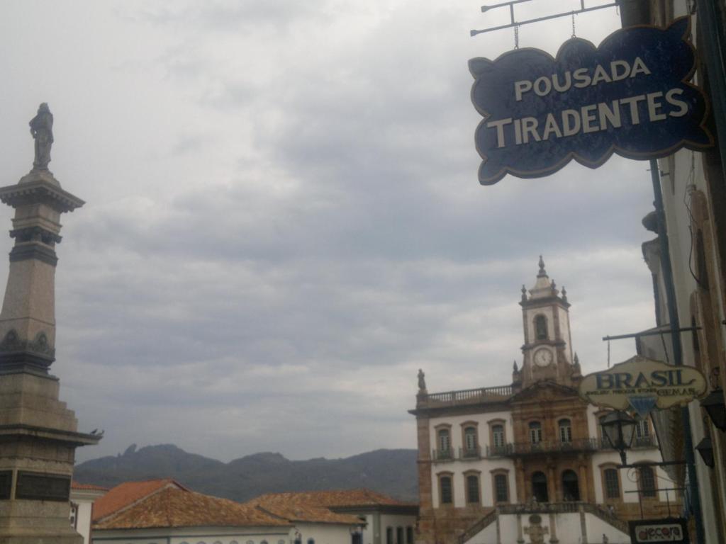 un cartello stradale in una città con un edificio di Pousada Tiradentes a Ouro Preto