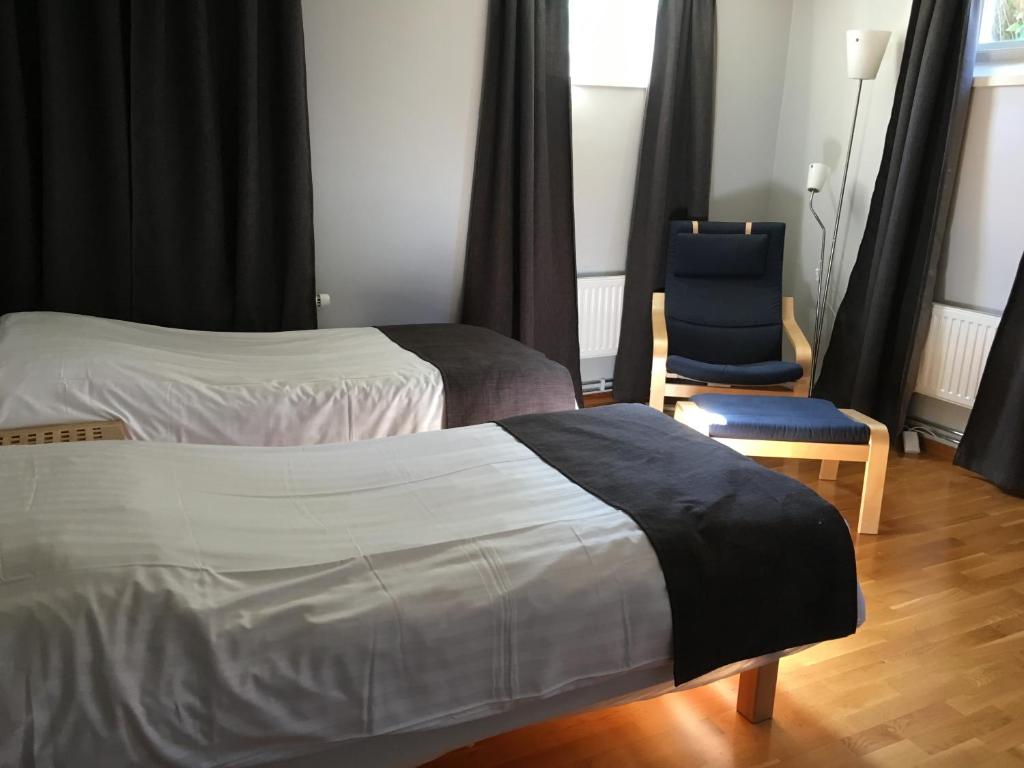 una habitación de hotel con 2 camas y una silla azul en Hotell Hässlö en Västerås