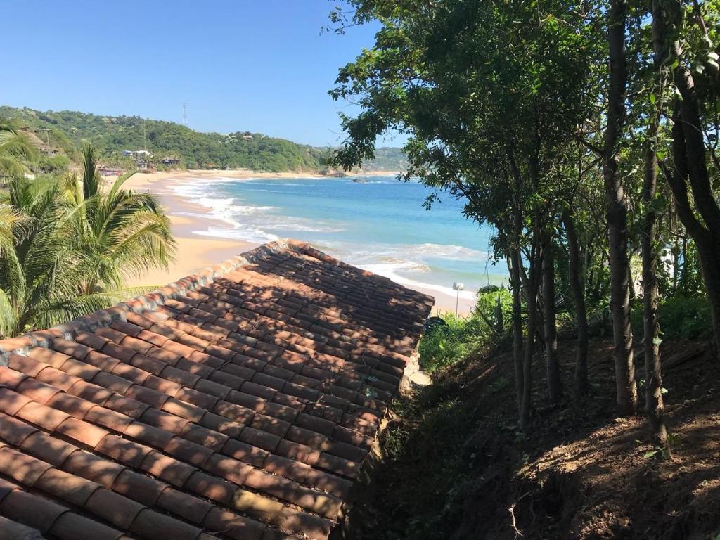 a view of a beach with a building and trees at La pajarera in Mazunte