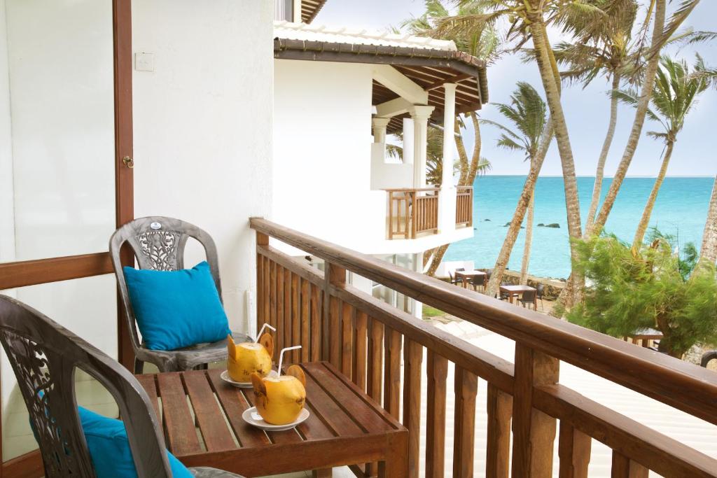 a table on a balcony with a view of the beach at Beach Inns Holiday Resort in Matara