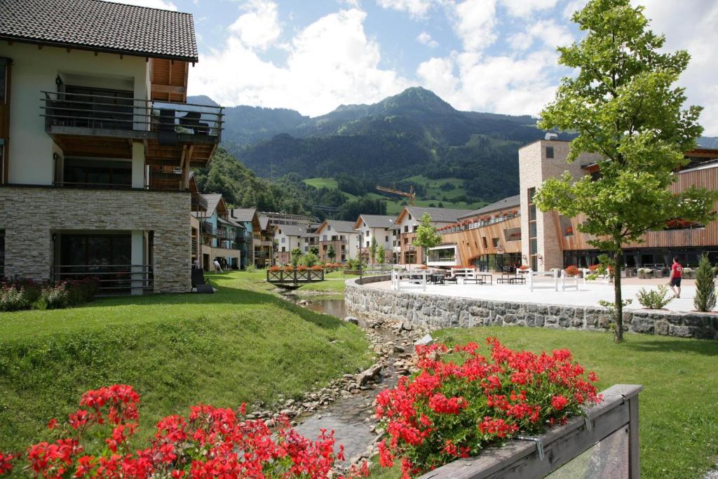 a town in the mountains with a river and flowers at Resort Walensee Appartements in Unterterzen