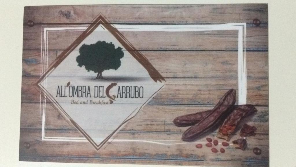 un disegno di un cartello su una parete di legno con del cibo di All'ombra del Carrubo - Metaponto a Metaponto