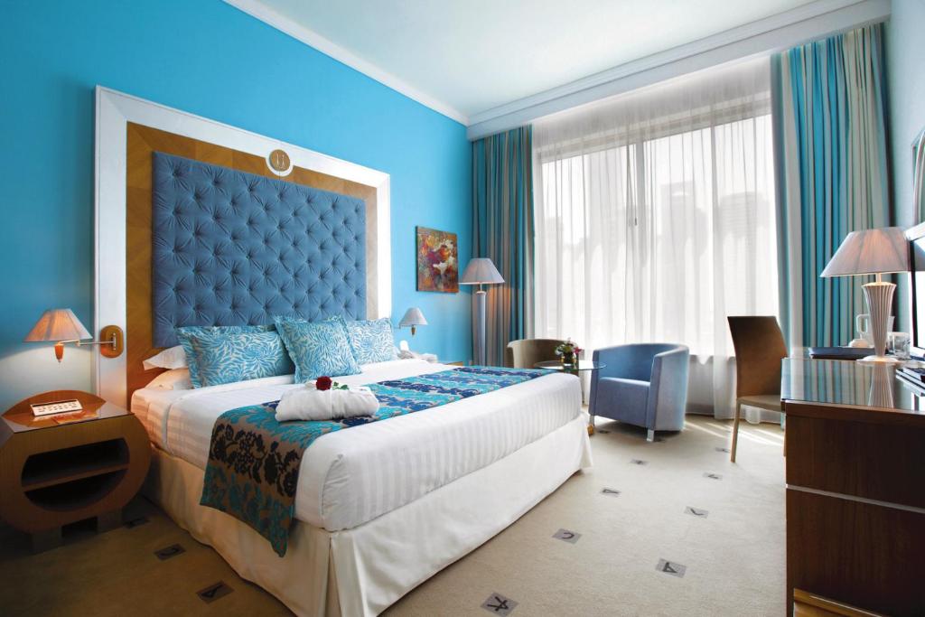 a bedroom with a large bed in a blue room at Marina Byblos Hotel in Dubai