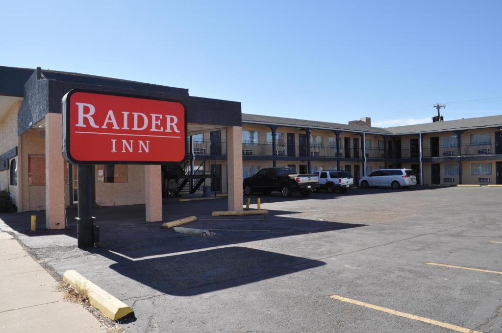 un cartel de la posada de un traficante rojo delante de un estacionamiento en Raider Inn en Lubbock