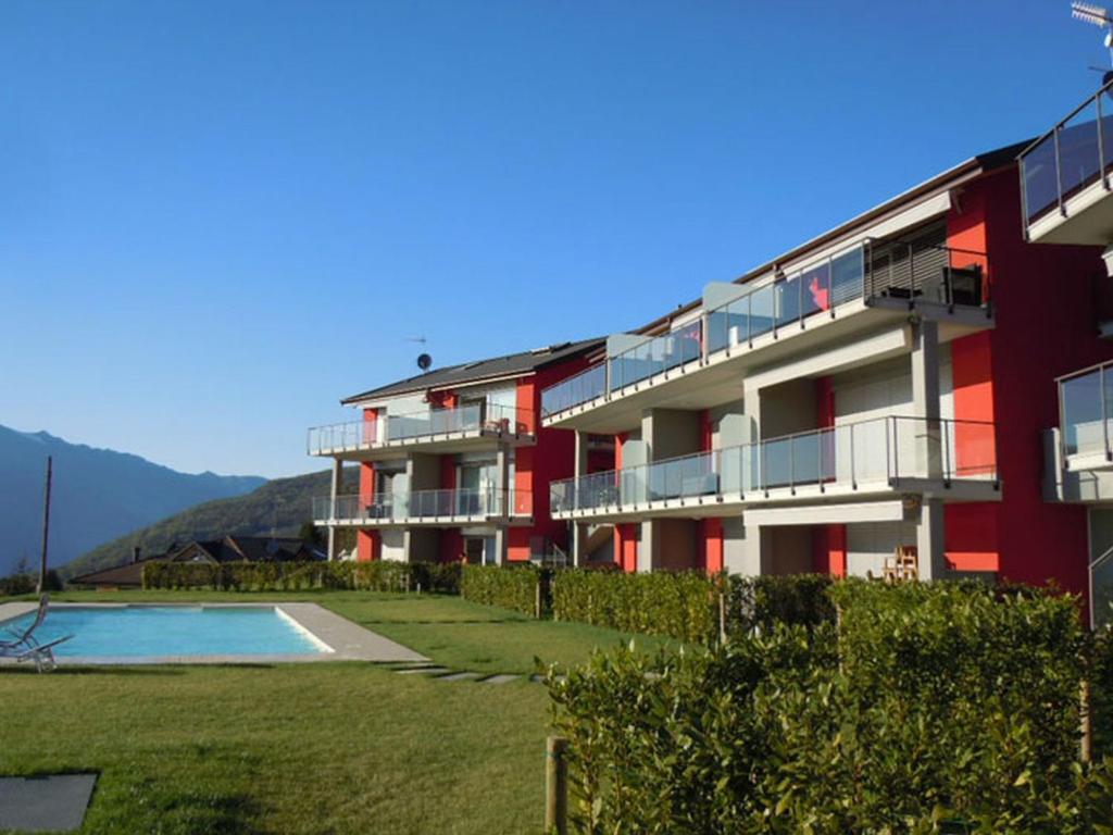 ein rotes Gebäude mit einem Pool davor in der Unterkunft Residenza Roggiolo in Luino