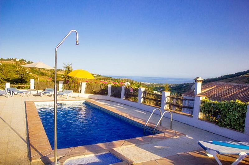 una piscina con sombrilla en una casa en Villa del Sol, en Frigiliana