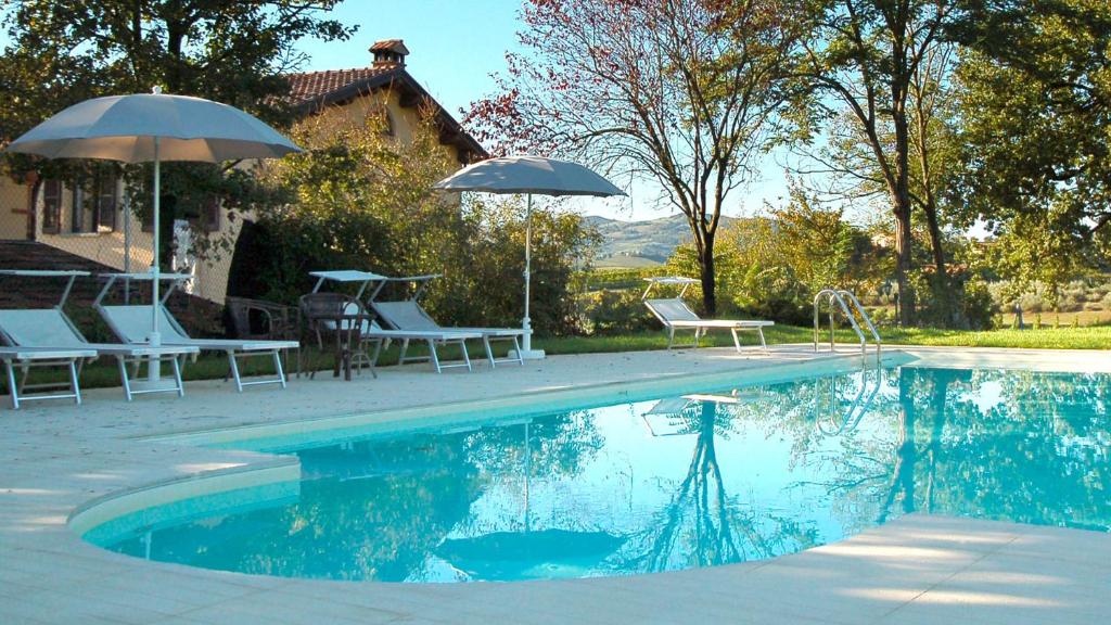 a pool with chairs and umbrellas next to a house at Locanda Camera con Vista in Faenza