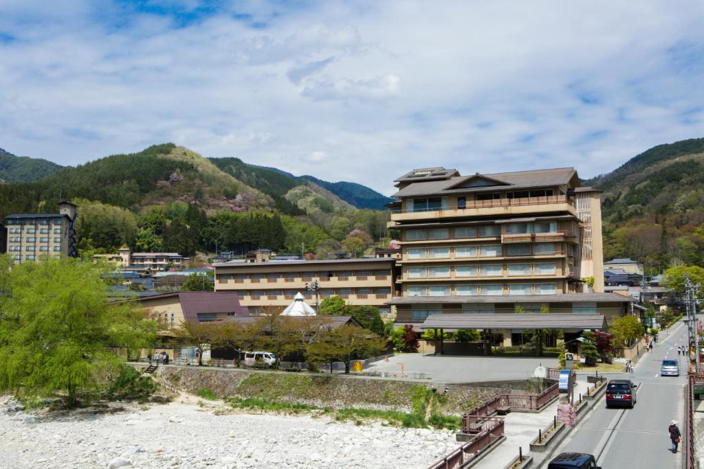 un gran edificio al lado de una carretera con montañas en Hirugami Grand Hotel Tenshin, en Achi