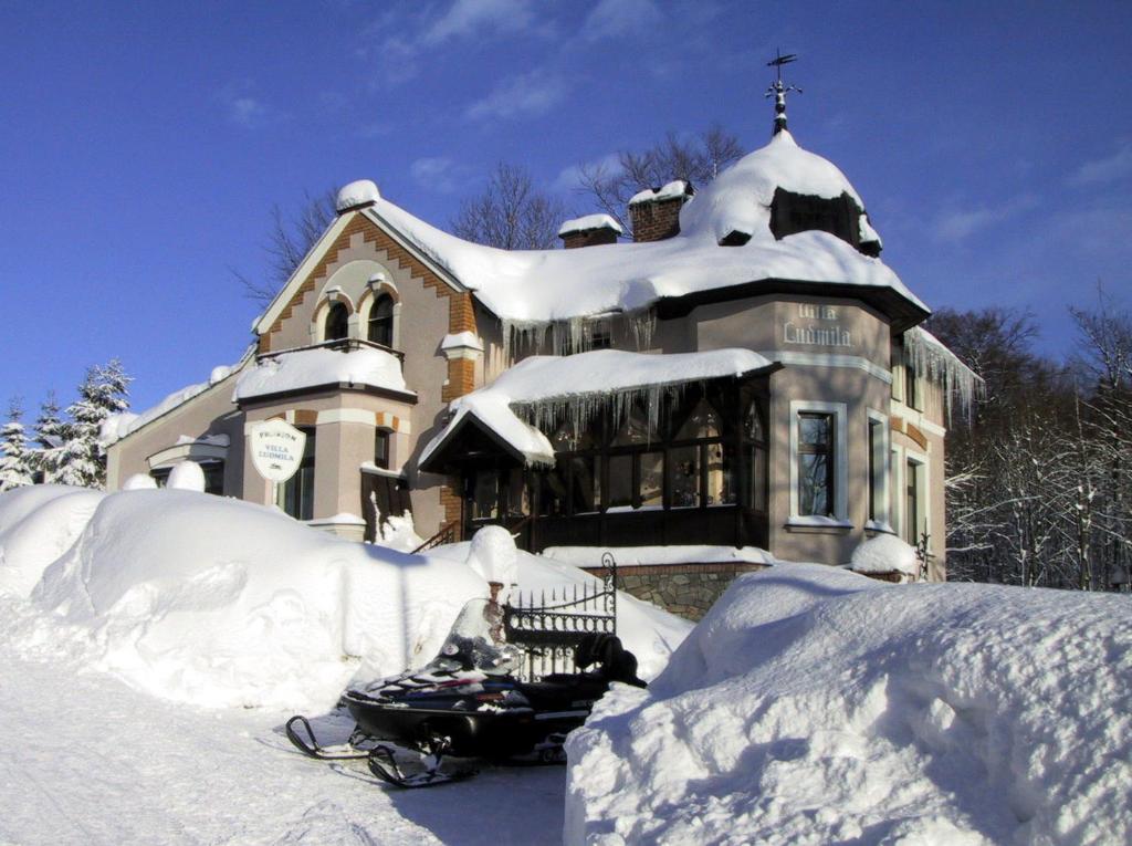 a snowmobile parked in front of a house covered in snow at Villa Ludmila in Janske Lazne