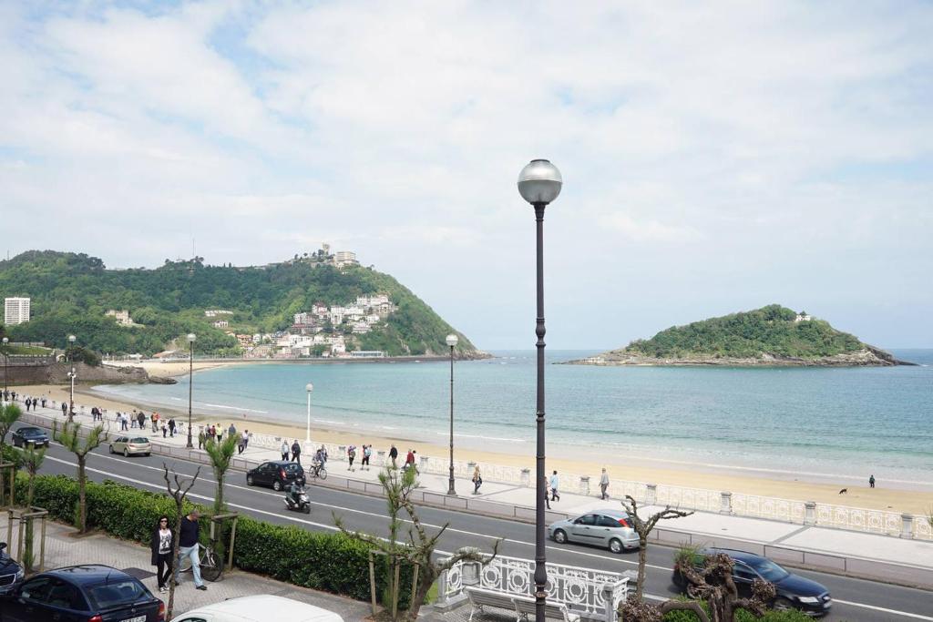 a view of a beach and a street with a street light at BREATHTAKING TERRACE VIEWS in luxury apartment - by www,SanSebastianApartments,es in San Sebastián