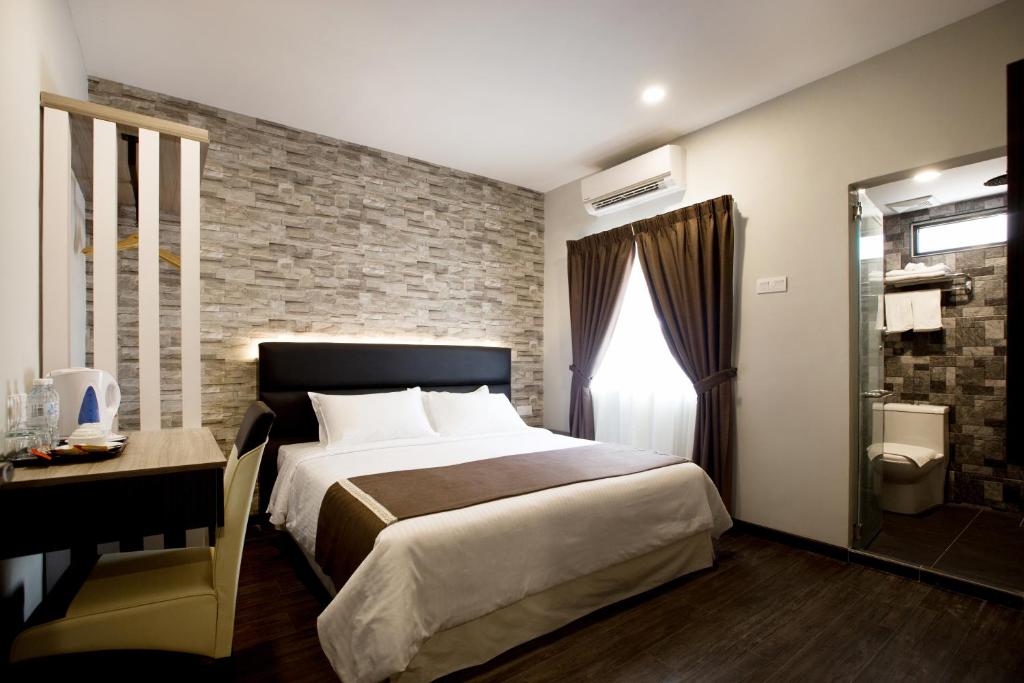 1 dormitorio con 1 cama grande y pared de ladrillo en Gurney Lodge en George Town