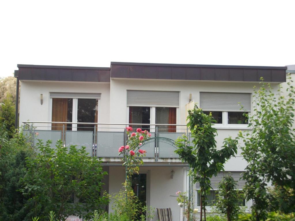 a white house with a balcony with pink flowers at TOM13 in Köngen