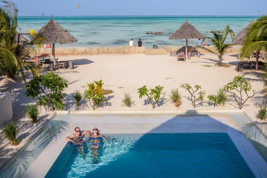 two people in a swimming pool next to a beach at Nur Beach Hotel in Jambiani
