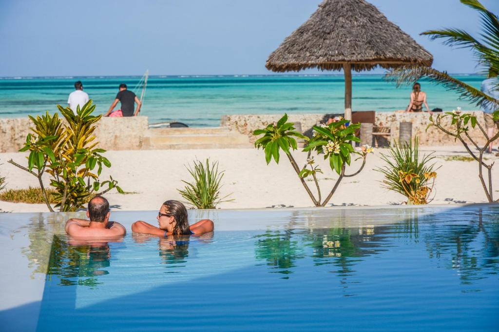 two people in the swimming pool at a beach at Nur Beach Hotel in Jambiani